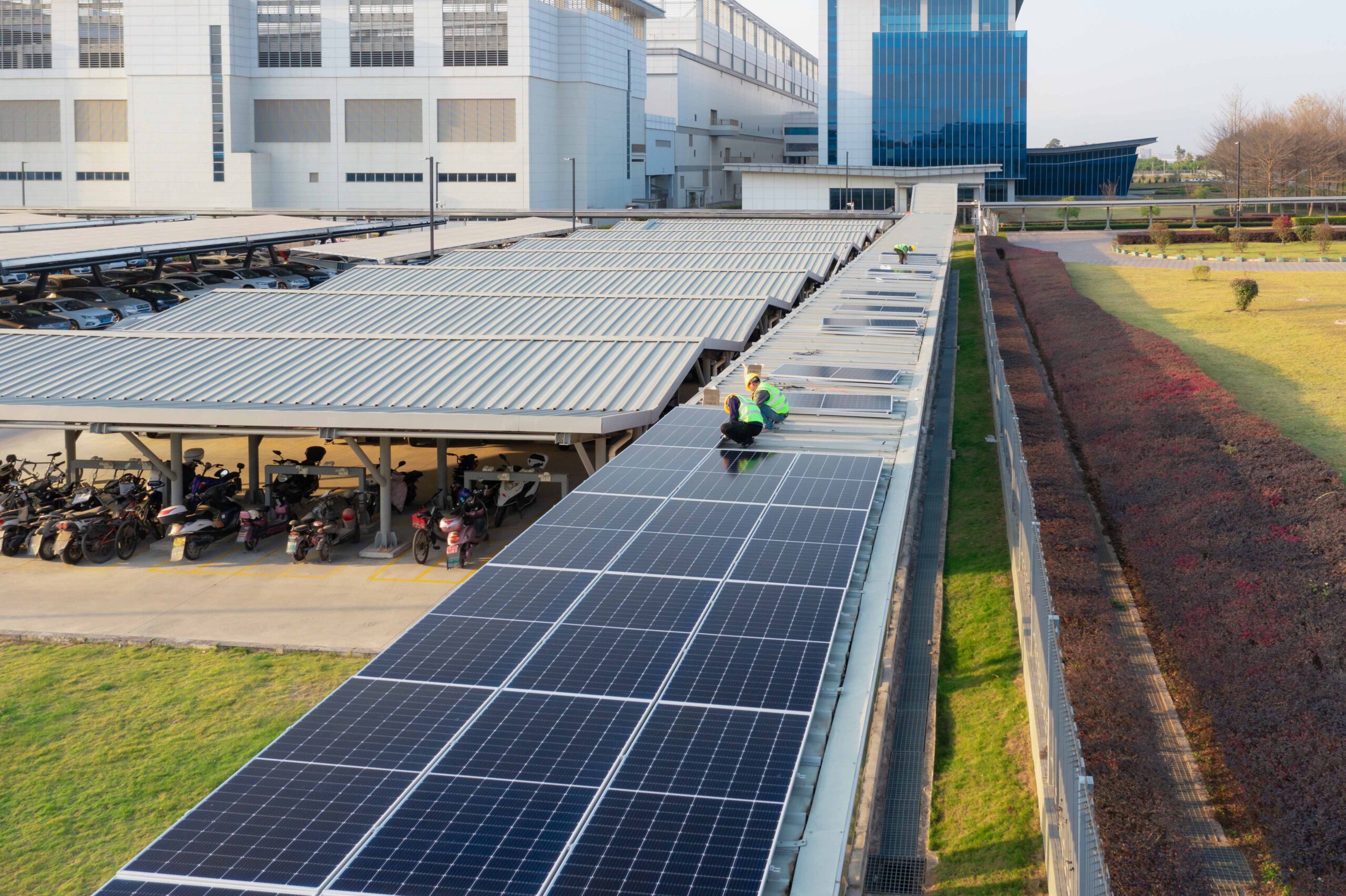 Arbeiter installieren eine Photovoltaikanlage auf dem Dach eines Parkplatzes