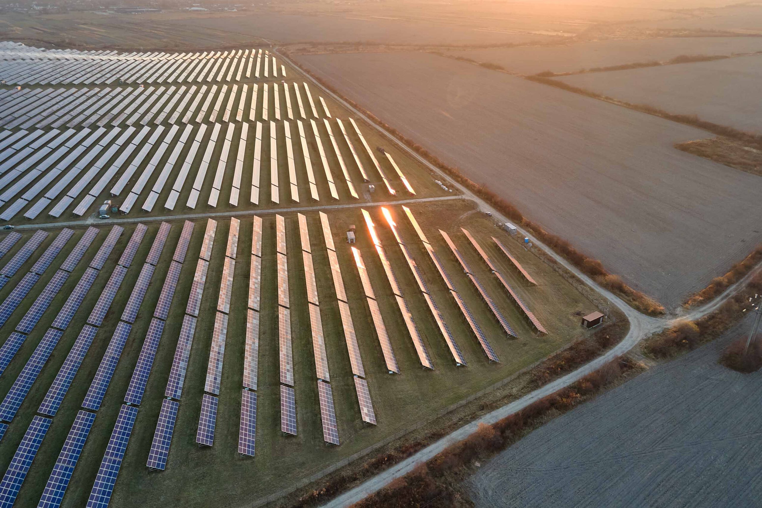 Solarpark auf einer Freifläche aus der Luft im Sonnenuntergang